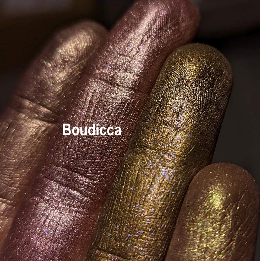 BOUDICCA frost finish eyeshadow shown loose and swatched on the skin. Boudicca is a strong plummy/russet brown, with complex highlight effects of green/gold and blue/teal.