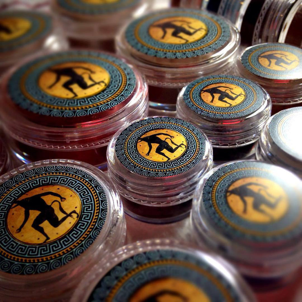 ARIADNE rouge product collage showing it loose and swatched on the skin. a soft red with glowing coppery shimmer.