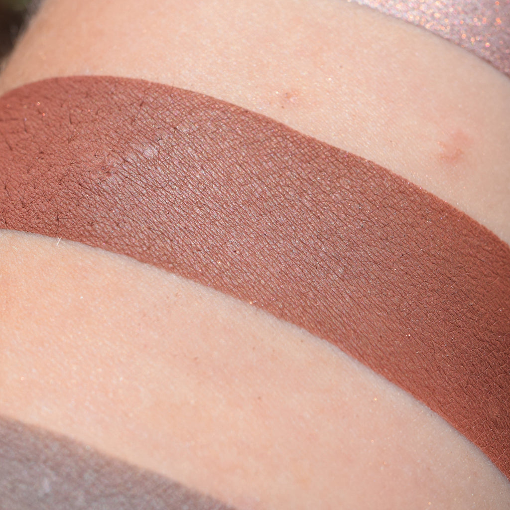 BACCHIC REVELRY- Multipurpose Contour/Eyeshadow loose and swatched on the skin. Rich terracotta brown/mahogany.