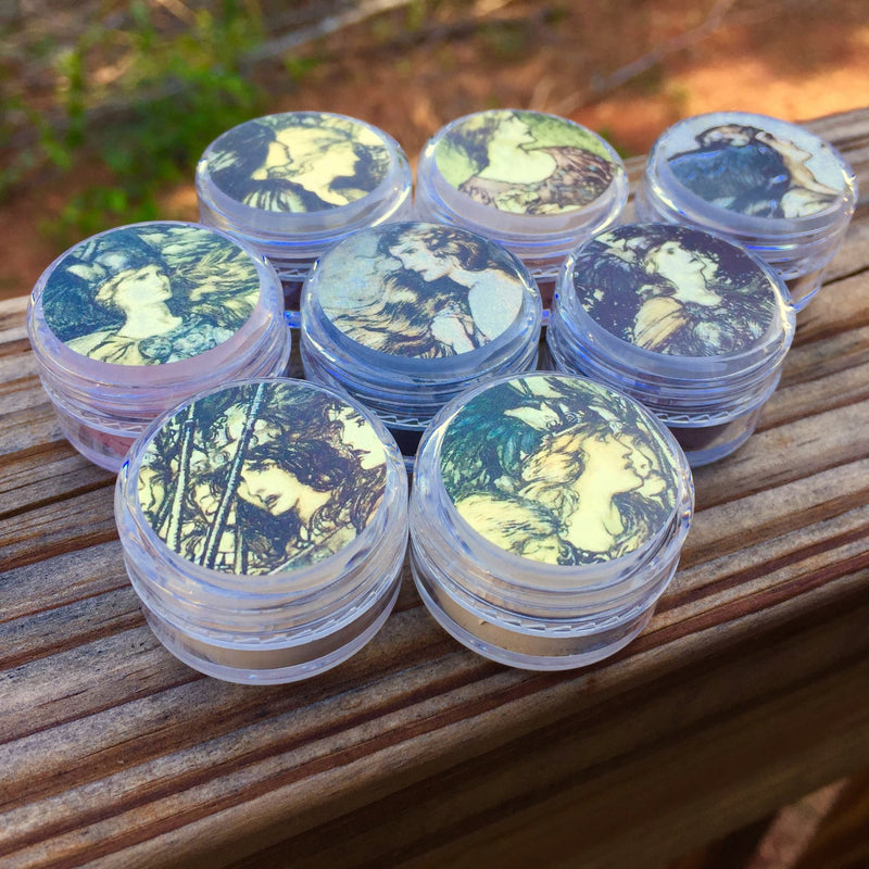 Jars of eyeshadow with round labels showing Norse women in different views by artist Arthur Rackham drawn in an earthy waterfolor/pencil style.