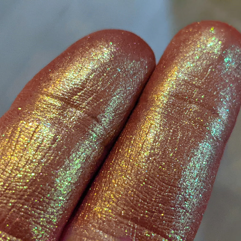Image showing closeup fingertip swatches of this shade, a deep orange red base with strong shimmering gold to green overlay of color.