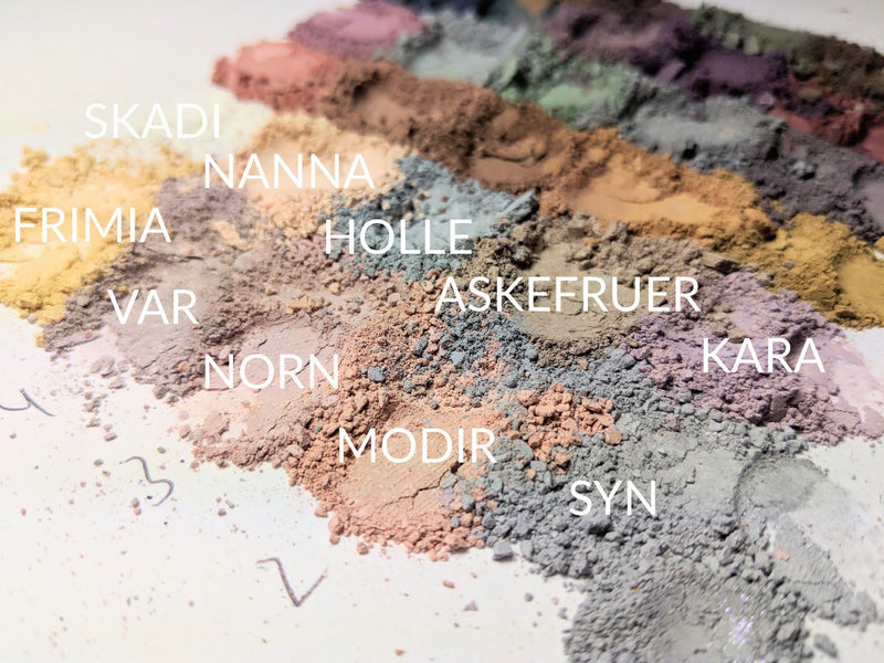 Piles of loose powder matte eyeshadow in pale shades. Kara is on the far right and is a pale muted lilac.