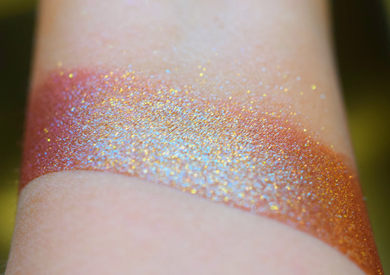 A skin swatch of Amanita on the inner arm, Image showing skin swatches of different views f this shade, It has a warm red base and strong gold to chartreuse color travel.