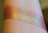 A skin swatch of Amanita on the inner arm, Image showing skin swatches of different views f this shade, It has a warm red base and strong gold to chartreuse color travel.