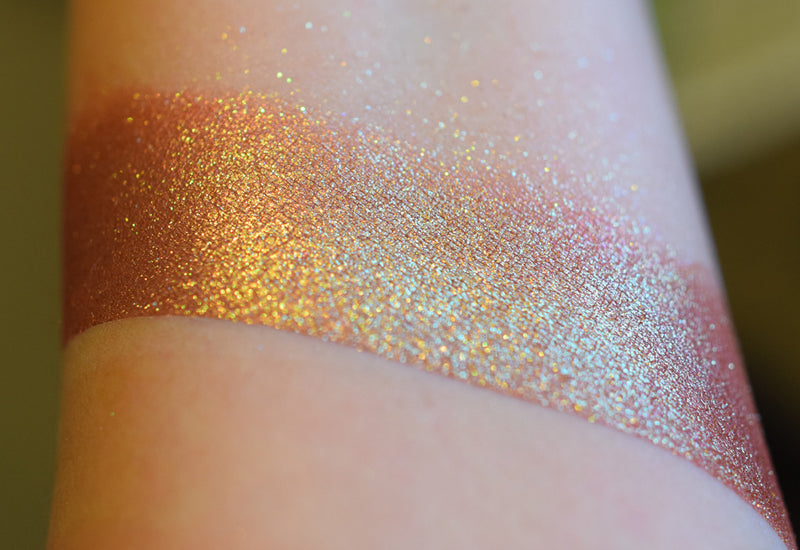 A skin swatch of Amanita on the inner arm, Image showing skin swatches of different views f this shade, It has a warm red base and strong gold to chartreuse color travel.