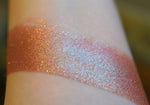 A skin swatch of Amanita on the inner arm, Image showing skin swatches of different views f this shade, It has a warm red base and strong gold to chartreuse color travel.