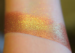 A skin swatch of Amanita on the inner arm, Image showing skin swatches of different views f this shade, It has a warm red base and strong gold to chartreuse color travel.