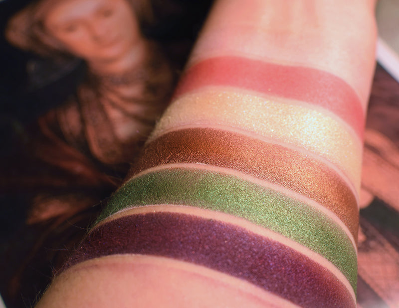 Skin swatches on the arm, of the eyeshadows in this collection. As a Maid is the second from the top, A buttery cream frost with sparks of pale violet and green.