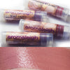 Lip balm tubes and a swatch of Conjured by Song on the skin. Neutral peachy buff