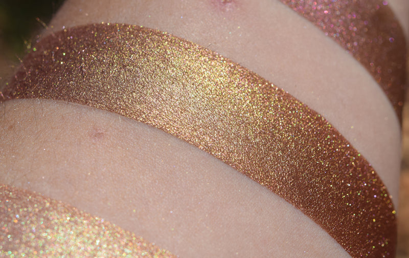 CRUEL FATES - EYESHADOW - swatched on inner arm caucasian skin. Coppery brown shifting to vibrant gold and greenish gold, as well as to a stronger copper.