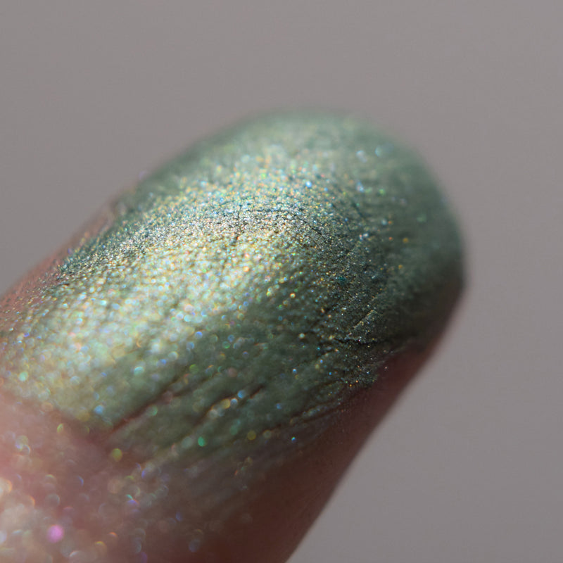 Aethelflaed shown close up on a fingertip. Image shows skin swatches of Adelaide eyeshadow, Aethelflaed is a vibrant true green with a green to chartreuse tonal effect