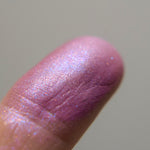 A closeup of Aspasia on a fingertip. an exquisite orchid purple, with hints of copper, teal and indigo iridescence.