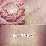 FORTUNA - Highlighter loose and swatched on the skin. Fortuna is a delicate warm pink with green iridescence