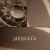 Jarnsaxa matte eyeshadow shown loose and swatched on the skin. Dark oak brown with olive tones