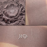 Jord matte eyeshadow shown loose and swatched on the skin. Midtone taupe