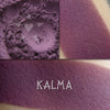 Kalma matte eyeshadow shown loose and swatched on the skin. Deep warm purple