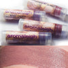 Transparent plastic lip balm tubes, and a skin swatch of Maenad, Taupe with rose and buff tones. I