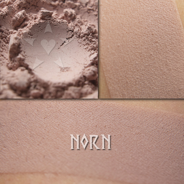 Norn matte eyeshadow shown loose and swatched on the skin. Pale taupe with pink and lilac undertones.