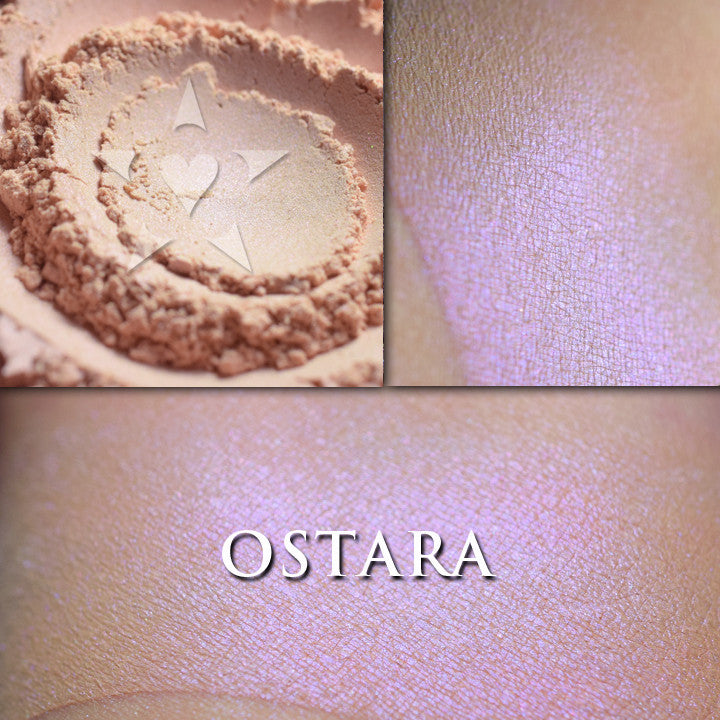 OSTARA highlighter loose and swatched on the skin. Ostara is a soft peach with a strong purple highlight. Jar labels feature the art of Alphonse Mucha.