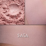 Saga matte eyeshadow shown loose and swatched on the skin. Soft petal pink
