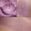 SALOME rouge shown loose and swatched on the skin. Salome is a warm violet with a soft luster.