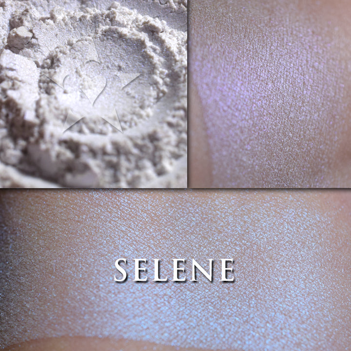 Selene highlighter loose and swatched on the skin. Selene appears white with a slight blue-violet tinge, but applied reveals a soft iridescent color shift that ranges from blue to violet.