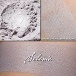 Selenia illuminator loose and swatched on the skin. A pale heathery lilac.