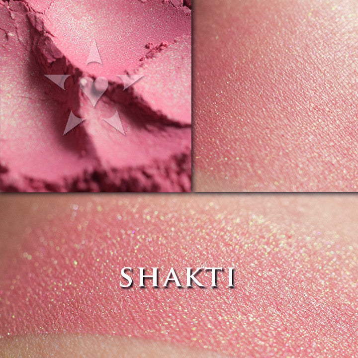 Shakti rouge loose and swatched on the skin. Shakti is a bright but wearable coral-pink with a strong green shift.