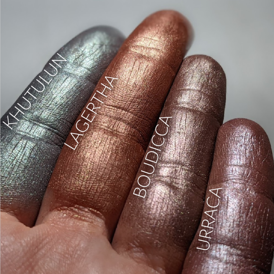 Finger swatches of green and brown frost eyeshadows. 