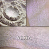 Vesta highlighter loose and swatched on the skin. Vesta appears white with a slight rose-violet tinge, but applied reveals a soft iridescent color shift that ranges from copper to rose to violet.