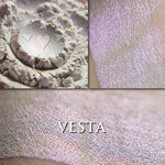 Vesta highlighter loose and swatched on the skin. Vesta appears white with a slight rose-violet tinge, but applied reveals a soft iridescent color shift that ranges from copper to rose to violet.