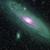 Space imagery showing a group of green and purple colored galaxies.