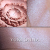 Yuki Onna highlighter loose and swatched on the skin. Yuki Onna is a delicate pale buffed peach with pronounced satiny blue interference highlight.