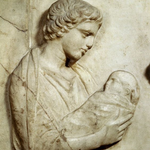 Image shows a bas relief sculpture of a woman holding a swaddled baby. She is Agnodice, who this eyeshadow is named after.