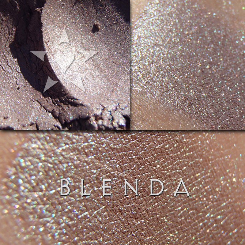BLENDA frost finish eyeshadow shown loose and swatched on the skin. It appears to be a buff shade with turquoise iridescence which then shifts to a rose-tinted taupe grey with blue and copper hilights.