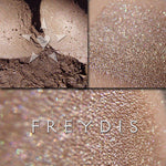 FREYDIS eyeshadow shown loose and swatched om the skin. A an wearable greyed mocha with a pale silvery sheen, and soft green/rose tonal effects.