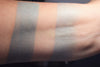 Lycaena swatched on medium tone caucasian skin, over primer and on bare skin. A pale heathery grey-blue
