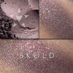 SKULD eyeshadow loose and swatched on the skin. Skuld has iridescent effects of red to violet, and copper tones, within a base of weathered red with dark violet undertones.