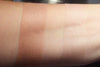 Thyatria swatched on medium tone caucasian skin, over primer and on bare skin. A muted peachy buff