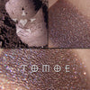 TOMOE eyeshadow shown loose and swatched on the skin.  Tomoe is an extremely dark brown which can look black, russet or violet toned, depending on the light. Veils of tonal color within this base shift the color with copper, blue and green.