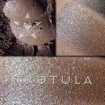 TROTULA eyeshadow shown loose and swatched on the skin. Trotula is a midtone greyed cocoa with a strong teal/blue/green interference that also appears very silvery in certain lighting.